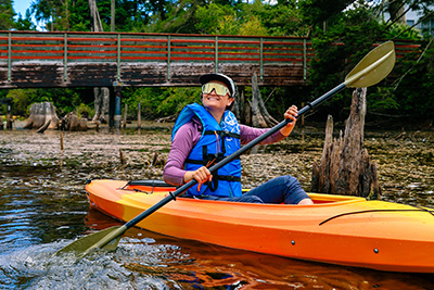 Woman with blue life vest and sunglasses, kayaking
