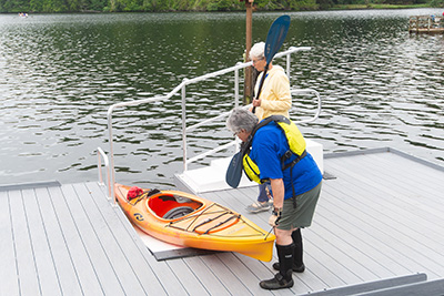 two women readying a kayak at an accessible launch into a lake
