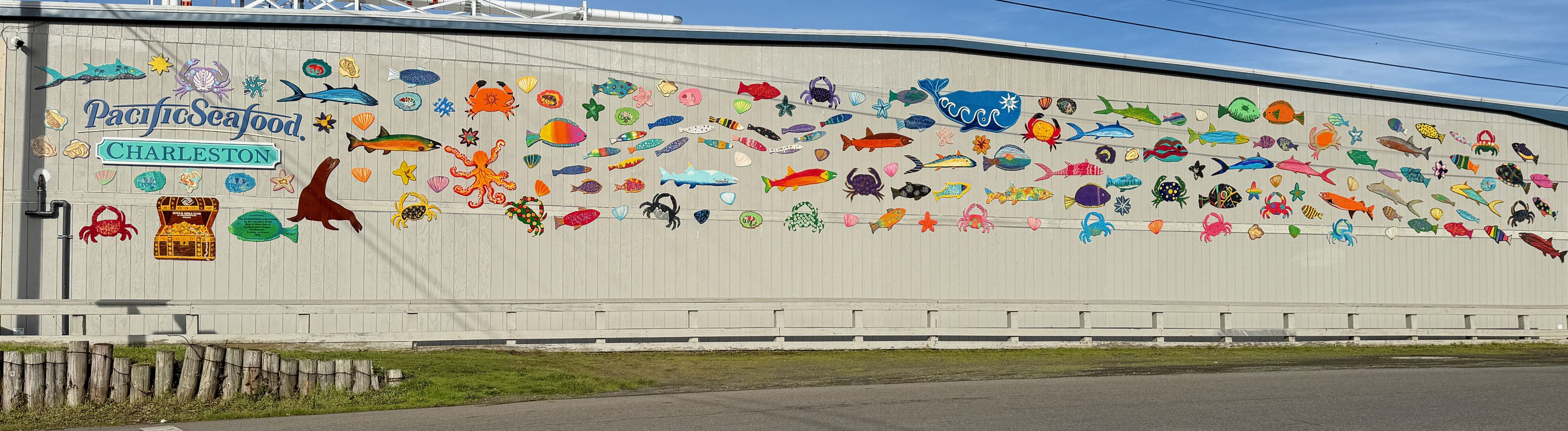 A mural of colorful fish adorn the outside of a warehouse building.