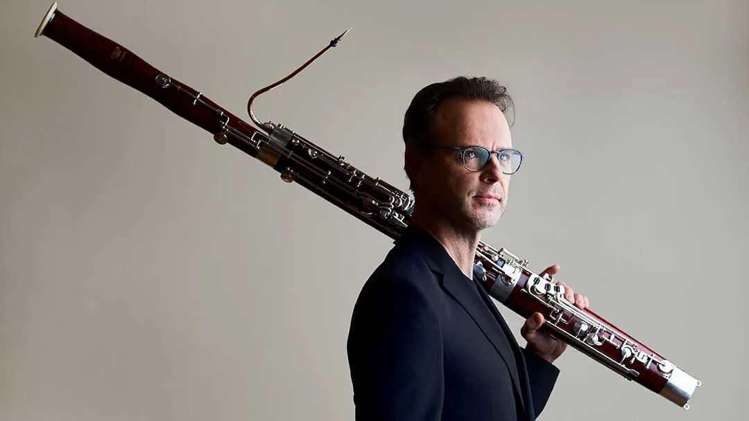 Bassoonist Martin Kuuskmann holding his bassoon.