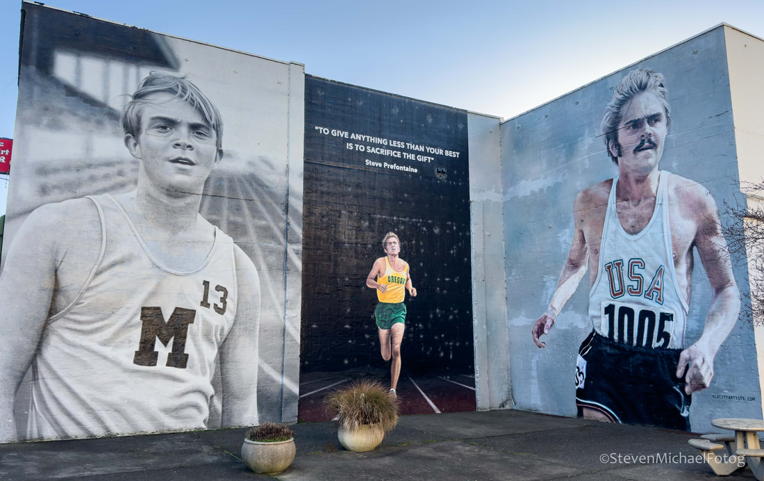 The Steve Prefontaine Murals in downtown Coos Bay, Oregon Large black and white mural spanning three building walls showing a runner at different stages of his career, including two close up portraits of Steve Prefontaine on either side and a full body image of him running on a track in the center, with an inspirational quote painted above the central figure.