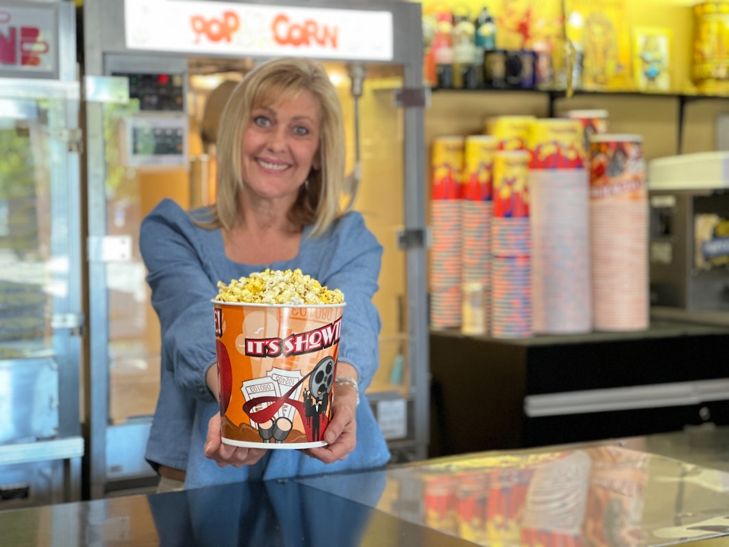 Egyptian Theatre Executive Director Jill Rasmusen serves popcorn with a smile at the concession stand inside the theatre’s lobby.